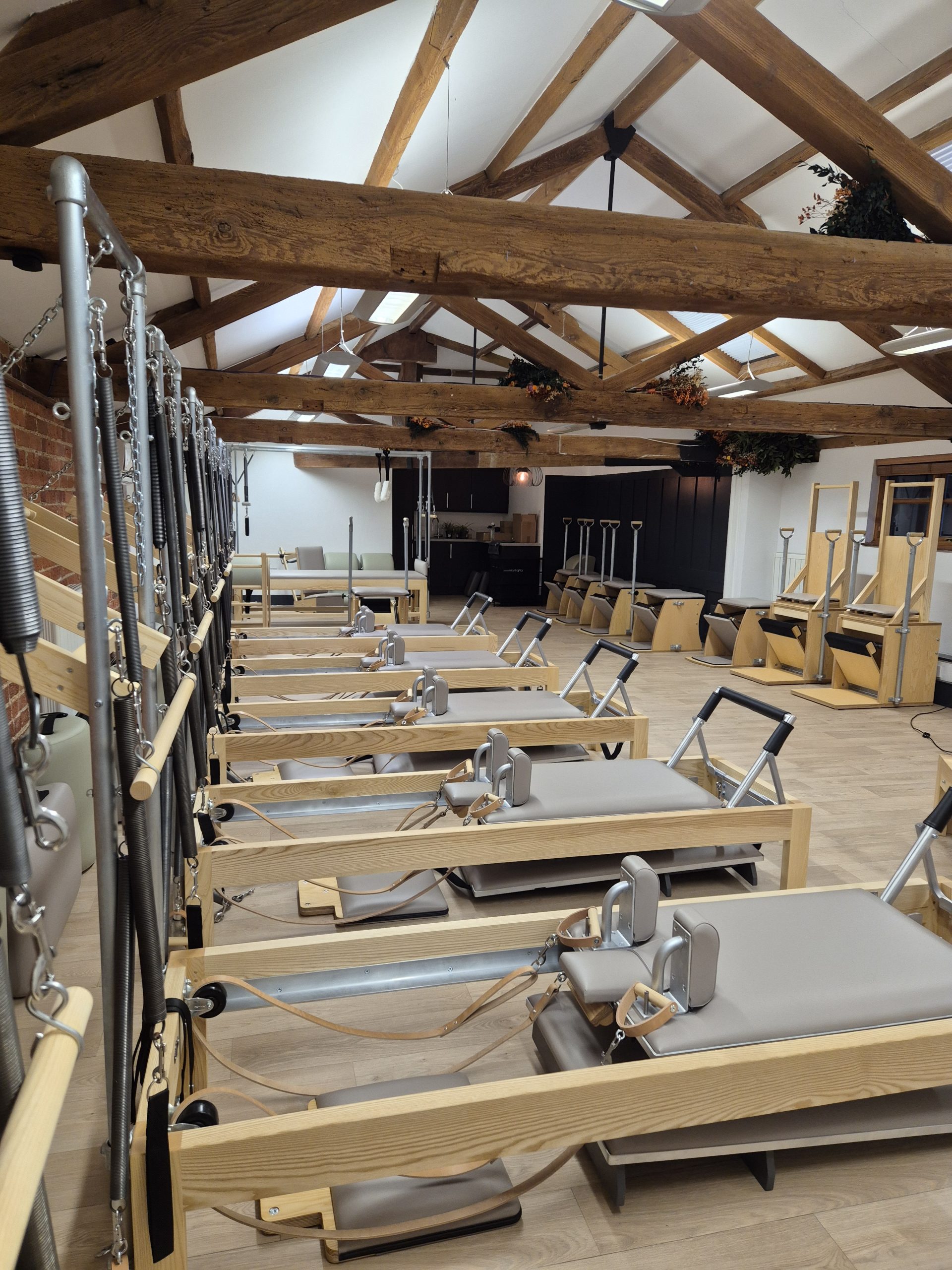 pilates studio with row of reformers, towers and chairs