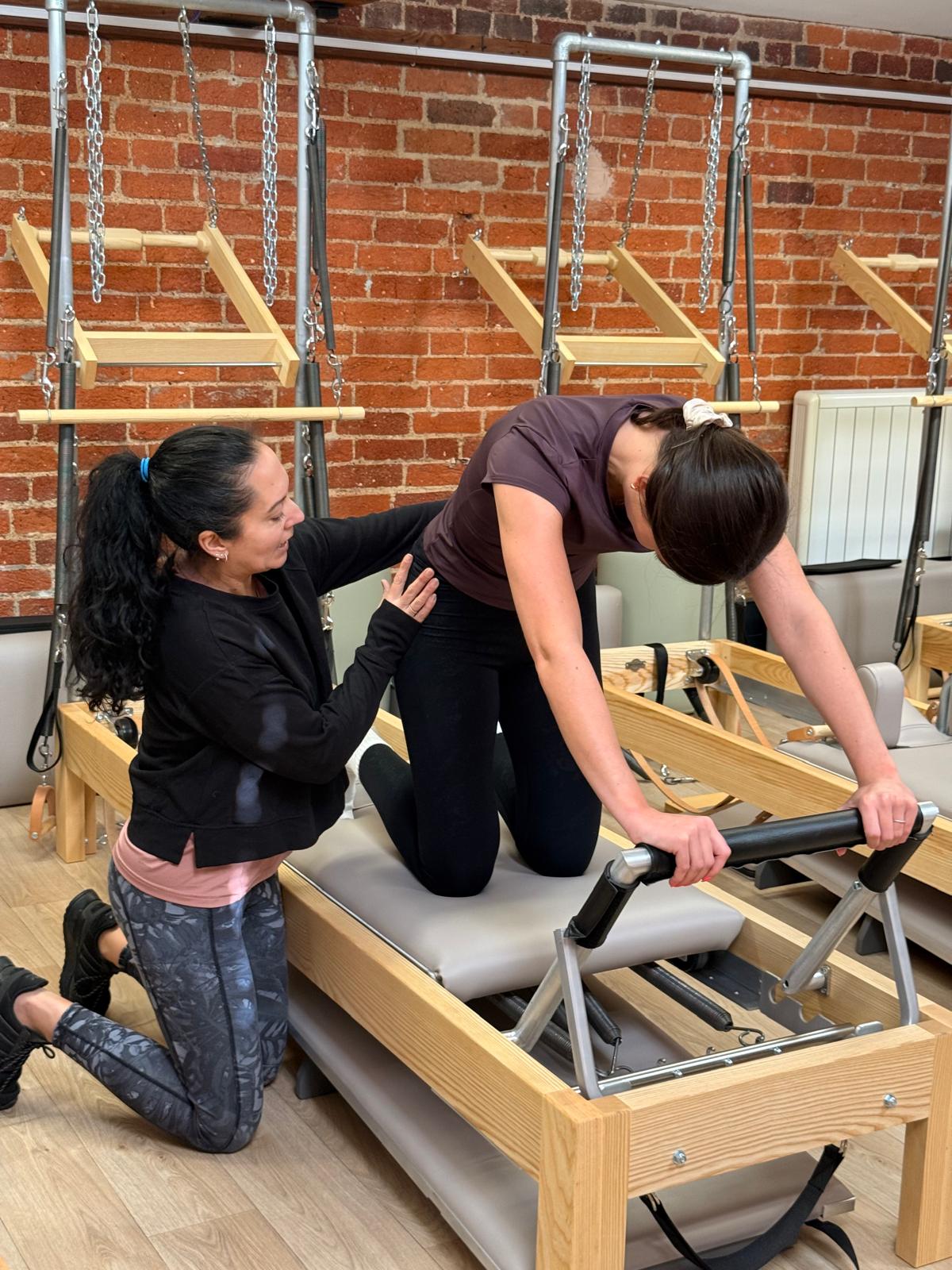 teacher helping client with posture on the reformer
